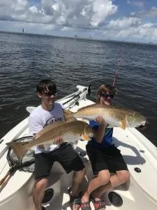 two boys each holding large redfish