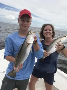mom and son each holding speckled trout