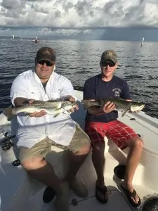two men each holding big speckled trout