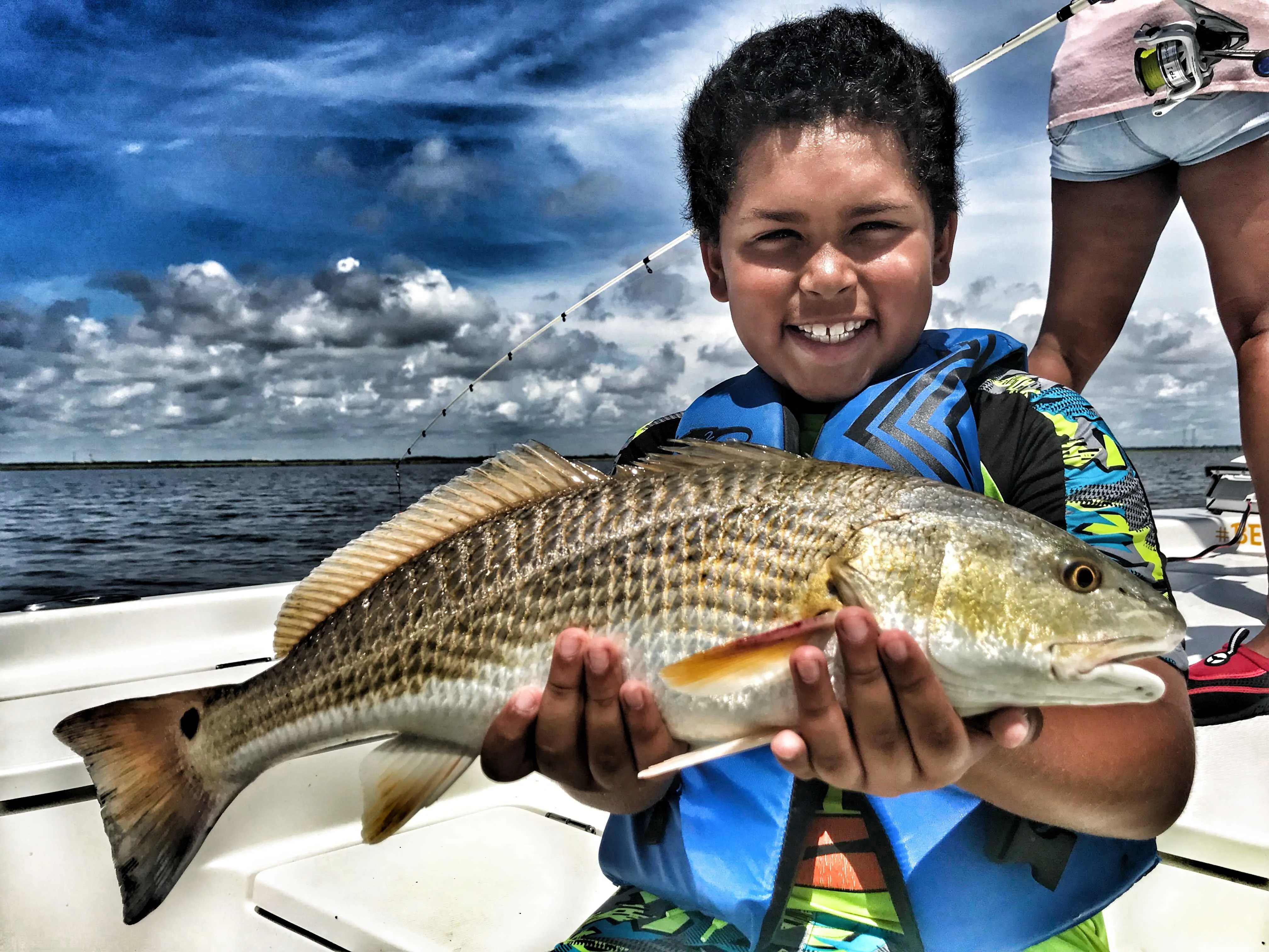 child-holding-redfish-on-boat