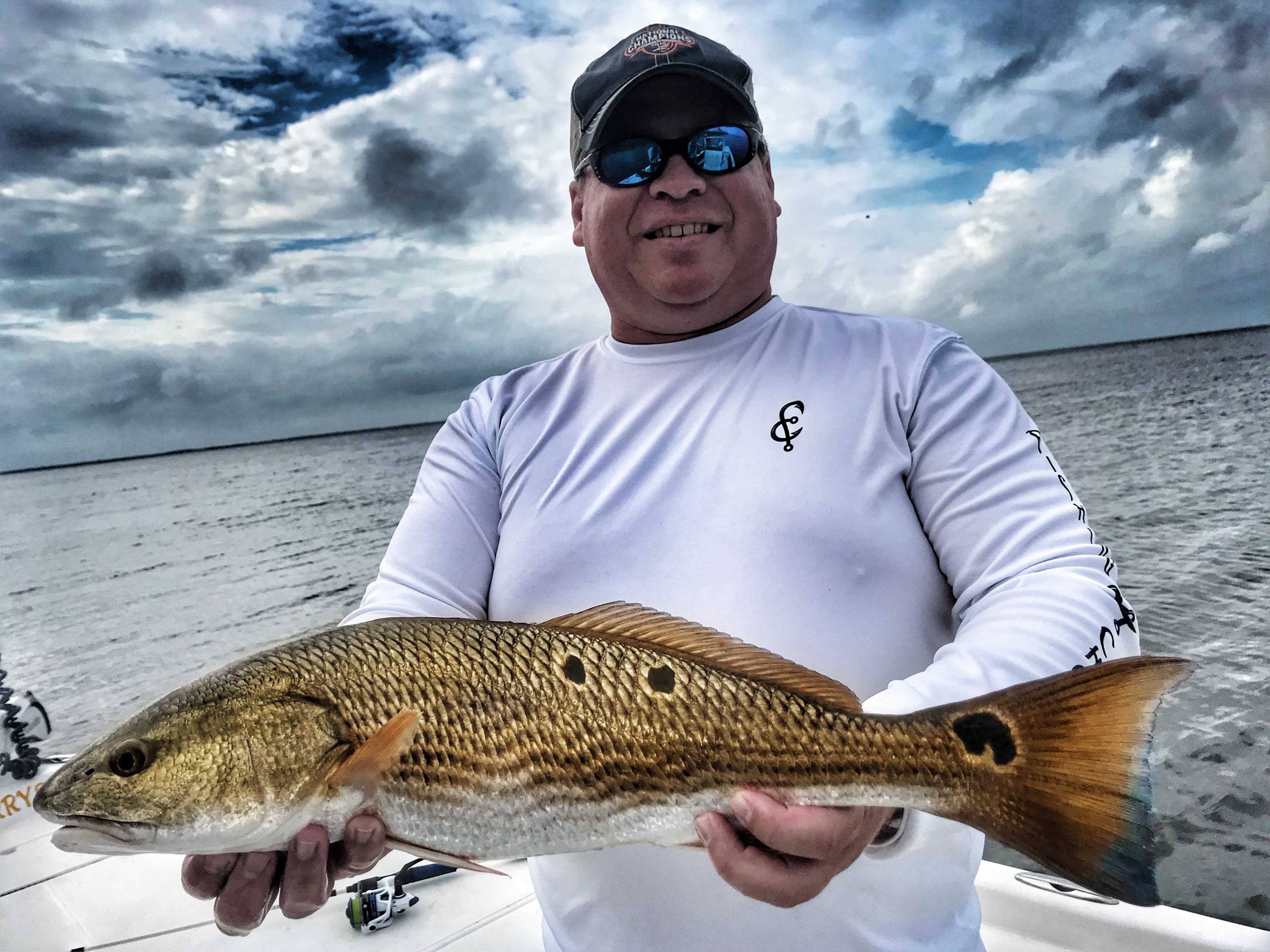 Man-wearing-fishing-chaos-shirt-holding-redfish