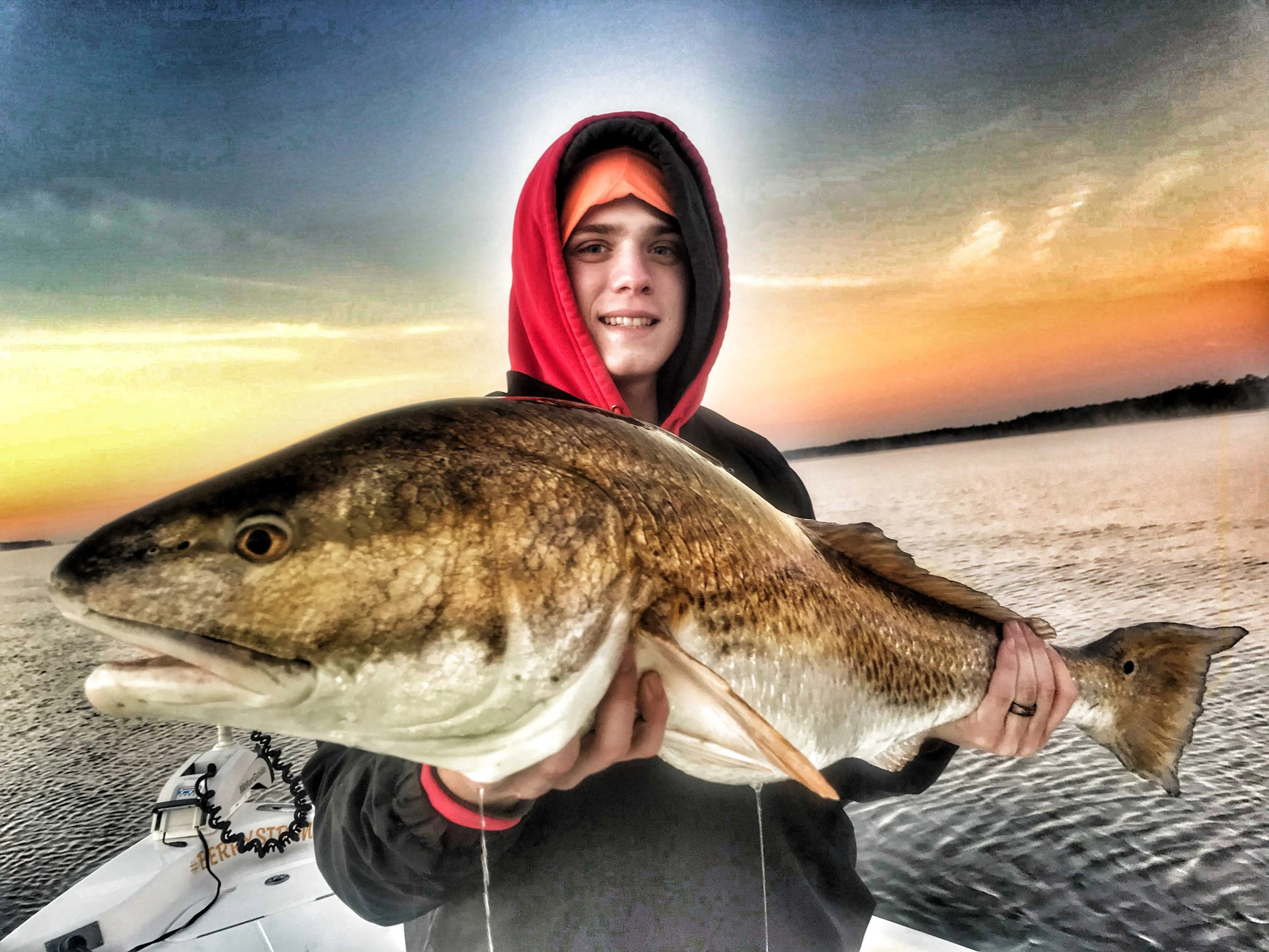 teenager-boy-holding-bull-redfish-before-sunrise