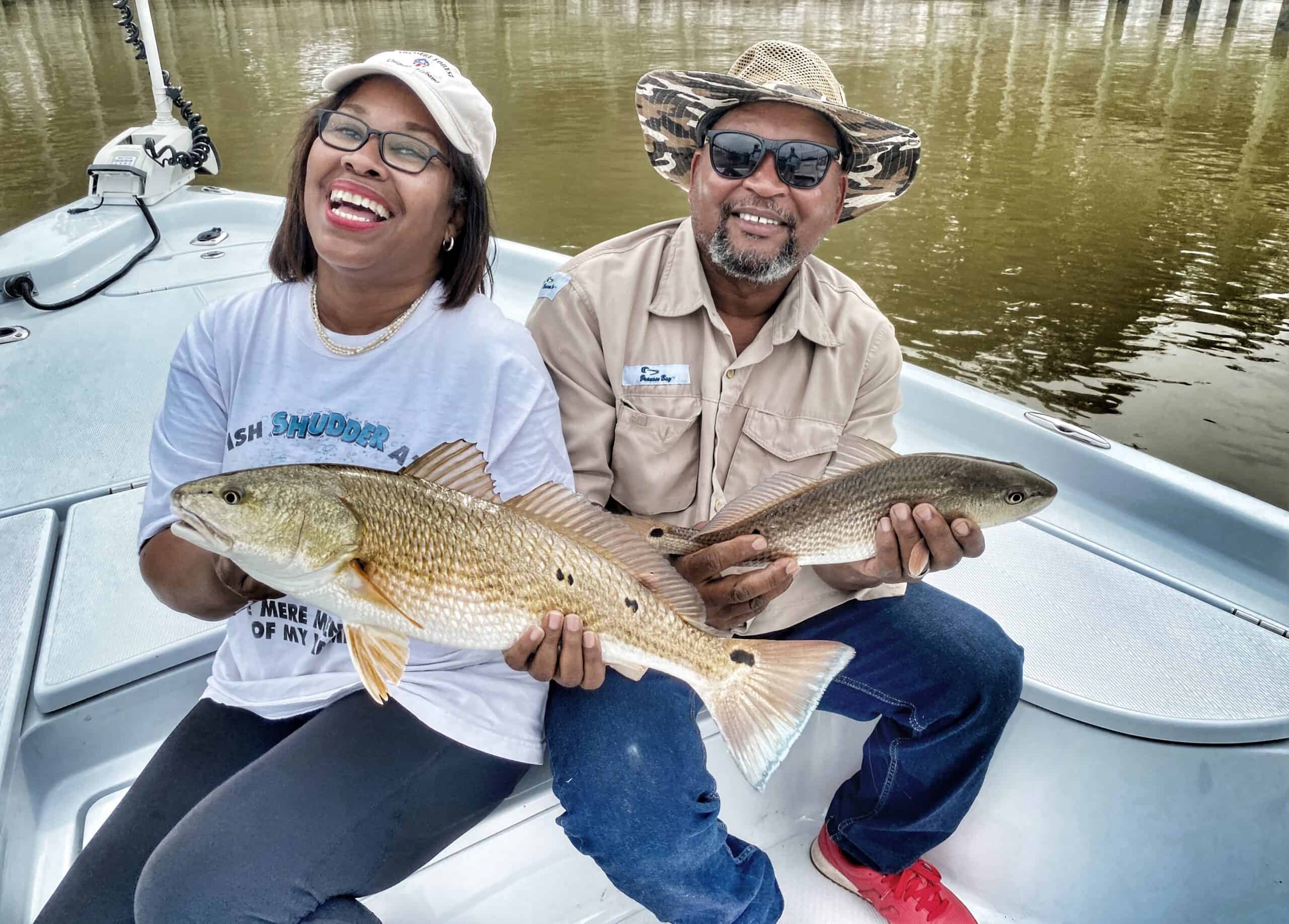Husband and wife holding redfish caught during a Fairhope fishing charter near Point Clear on Alabama’s Eastern Shore