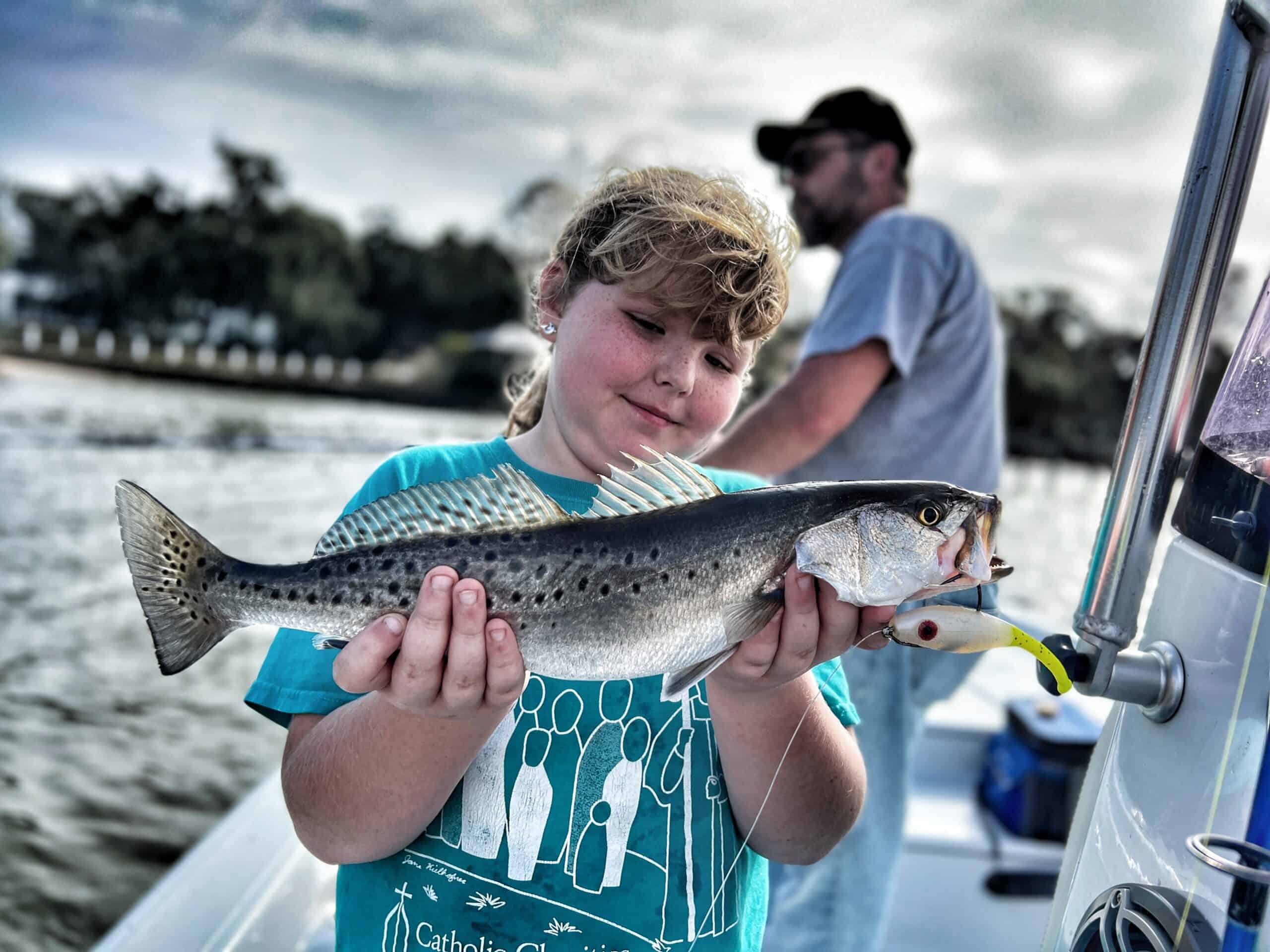 Young angler holding a speckled trout caught during a Fairhope fishing charter on Alabama’s Eastern Shore