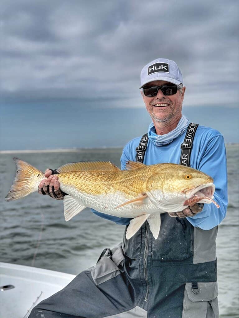 man holding redfish he caught while sight fishing Mobile Bay with Ugly Fishing